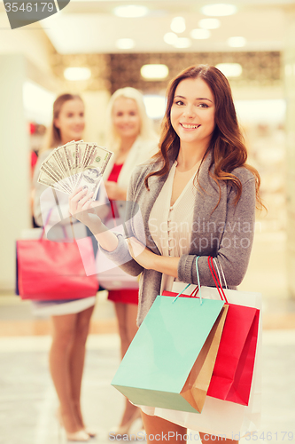 Image of young women with shopping bags and money in mall