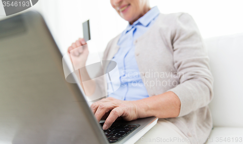 Image of senior woman with laptop and credit card at home