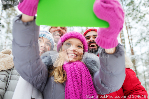 Image of smiling friends with tablet pc in winter forest