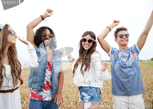 Image of happy young hippie friends dancing outdoors