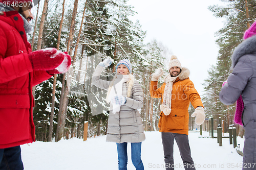 Image of happy friends playing snowball in winter forest