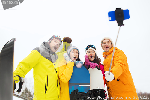 Image of happy friends with snowboards and smartphone