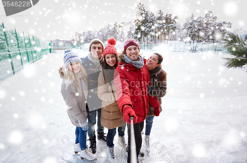 Image of happy friends with smartphone on ice skating rink