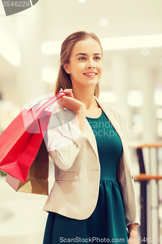 Image of happy young woman with shopping bags in mall