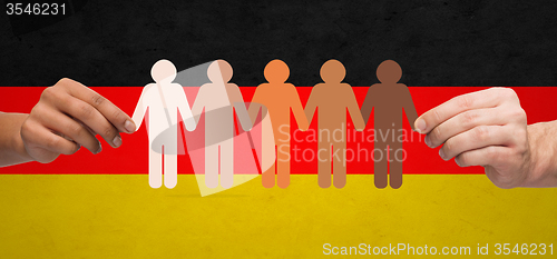 Image of hands with paper people pictogram over german flag