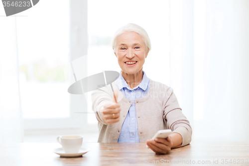 Image of senior woman with smartphone showing thumbs up
