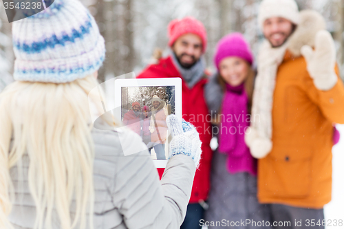 Image of happy friends with tablet pc in winter forest