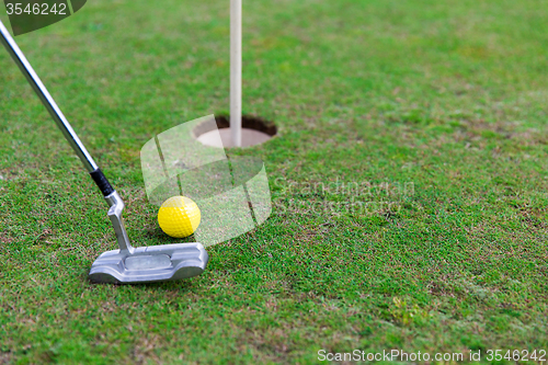 Image of close up of club and ball near hole on golf field