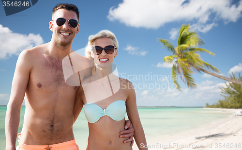 Image of happy couple in swimwear hugging over summer beach