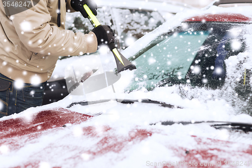 Image of closeup of man cleaning snow from car