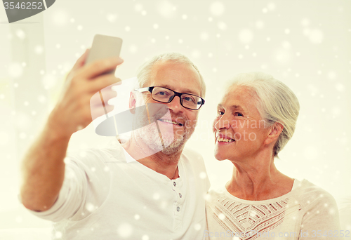 Image of happy senior couple with smartphone at home