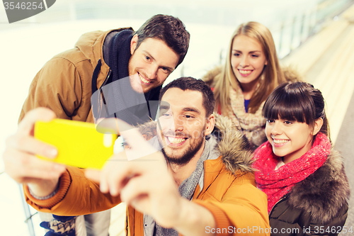 Image of happy friends with smartphone on skating rink