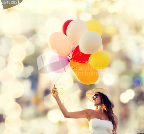 Image of smiling young woman in sunglasses with balloons