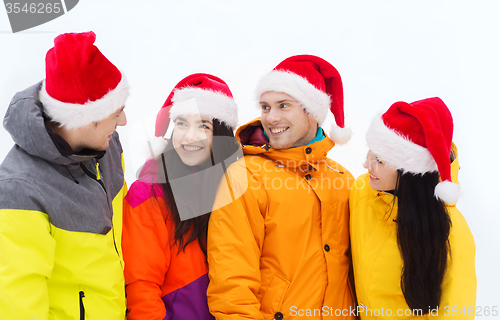 Image of happy friends in santa hats and ski suits outdoors