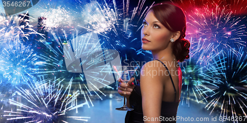 Image of woman holding cocktail over firework in city