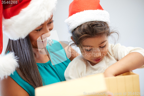 Image of happy mother and child in santa hats with gift box