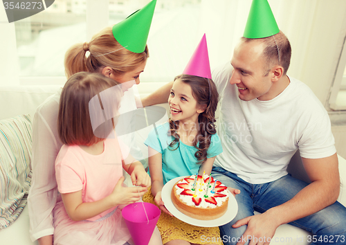 Image of smiling family with two kids in hats with cake