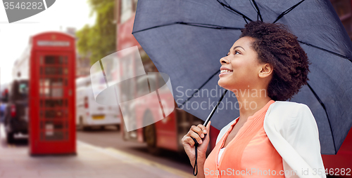 Image of happy african woman with umbrella in london city