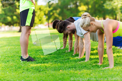 Image of group of friends or sportsmen exercising outdoors