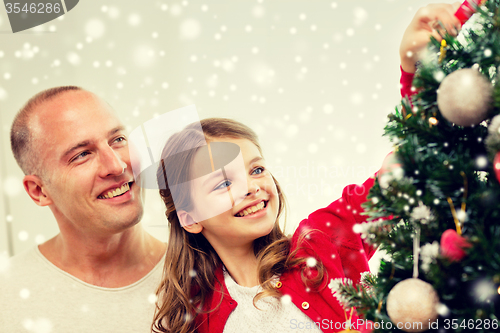 Image of smiling family decorating christmas tree at home