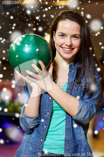 Image of happy young woman holding ball in bowling club