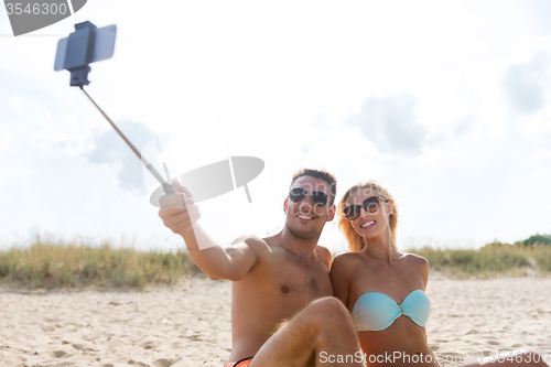 Image of happy couple in swimwear sitting on summer beach