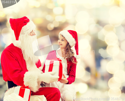 Image of smiling little girl with santa claus and gifts