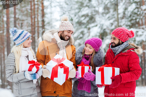 Image of happy friends with gift boxes in winter forest