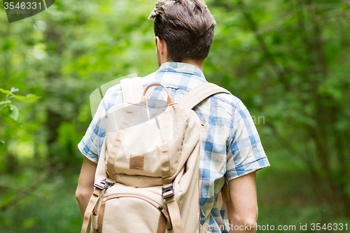 Image of young man with backpack hiking in woods