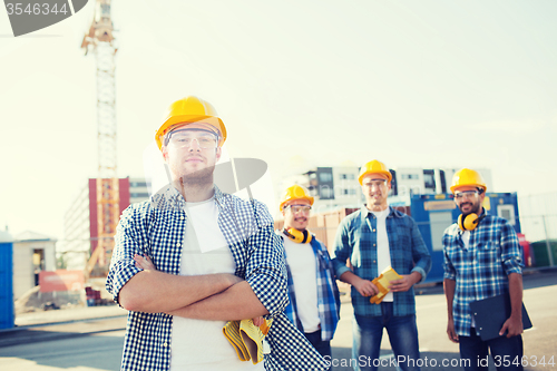 Image of group of smiling builders in hardhats outdoors