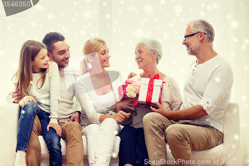 Image of happy family with bunch and gift box at home