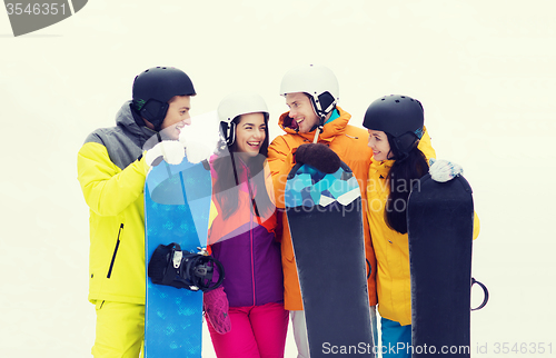 Image of happy friends in helmets with snowboards talking