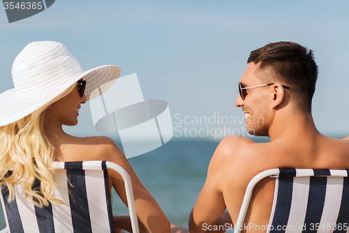 Image of happy couple sunbathing in chairs on summer beach