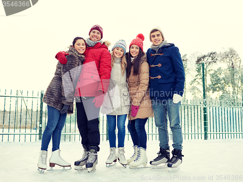 Image of happy friends ice skating on rink outdoors