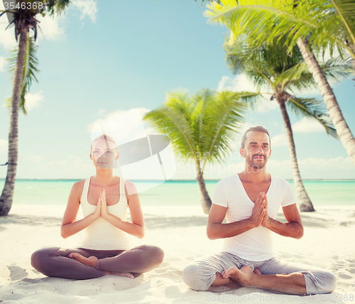Image of smiling couple meditating on tropical beach