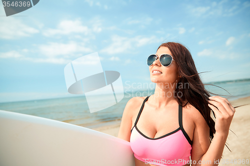 Image of smiling young woman with surfboard on beach