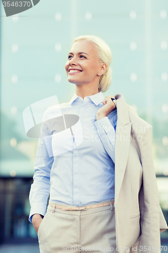 Image of young smiling businesswoman over office building