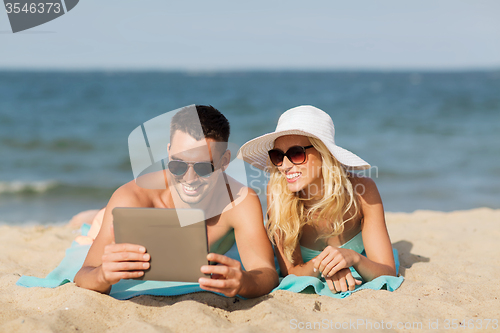 Image of happy couple with tablet pc sunbathing on beach