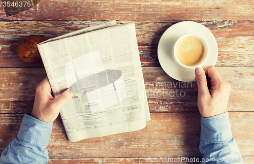 Image of close up of male hands with newspaper and coffee