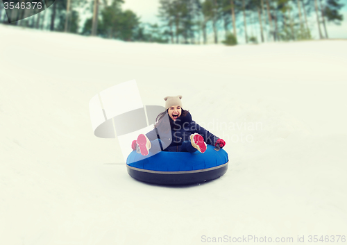 Image of happy teenage girl sliding down on snow tube