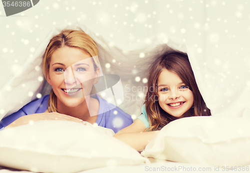 Image of happy mother and girl under blanket at home