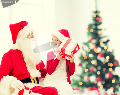 Image of smiling little girl with santa claus and gifts