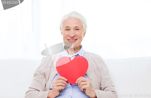 Image of happy smiling senior woman with red heart at home