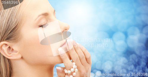 Image of beautiful woman with sea pearl beads over blue