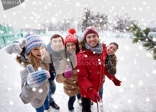 Image of happy friends with smartphone on ice skating rink