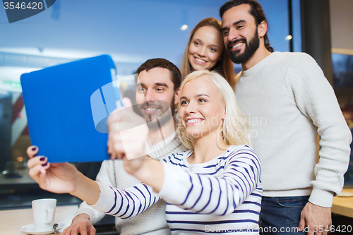 Image of happy friends with tablet pc taking selfie at cafe