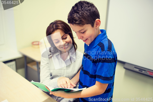 Image of school boy with notebook and teacher in classroom