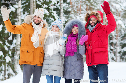 Image of group of friends waving hands in winter forest