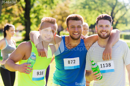 Image of happy friends with racing badge numbers and water