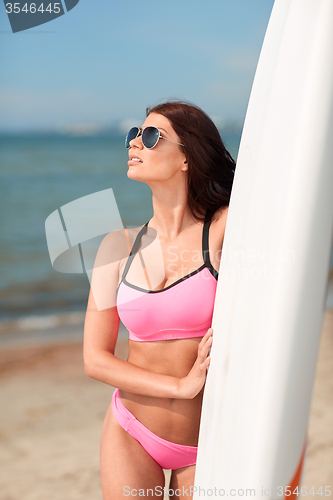 Image of smiling young woman with surfboard on beach